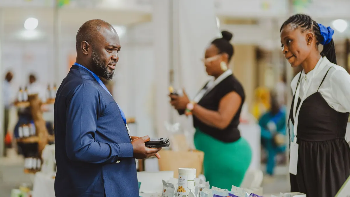Business professionals interacting at a trade show in Accra, Ghana, showcasing products and engaging in conversation.