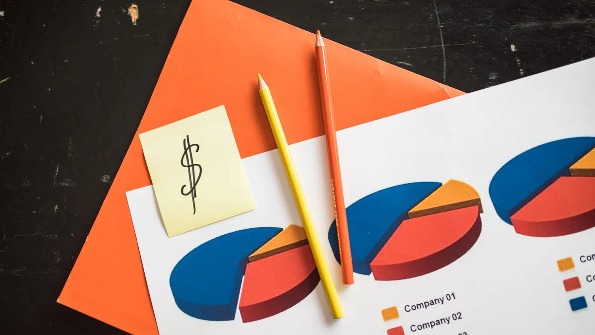 A creative arrangement of financial pie charts with colorful pencils and a dollar note, perfect for business themes.