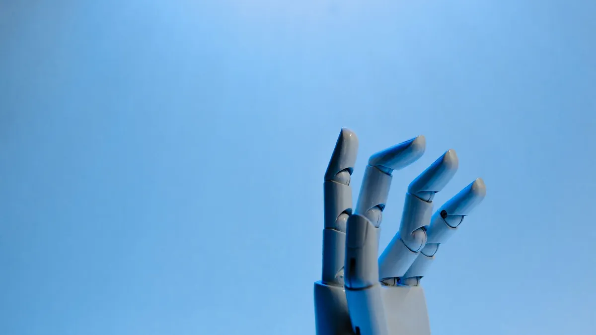 Robotic hand with articulated fingers reaching towards the sky on a blue background.