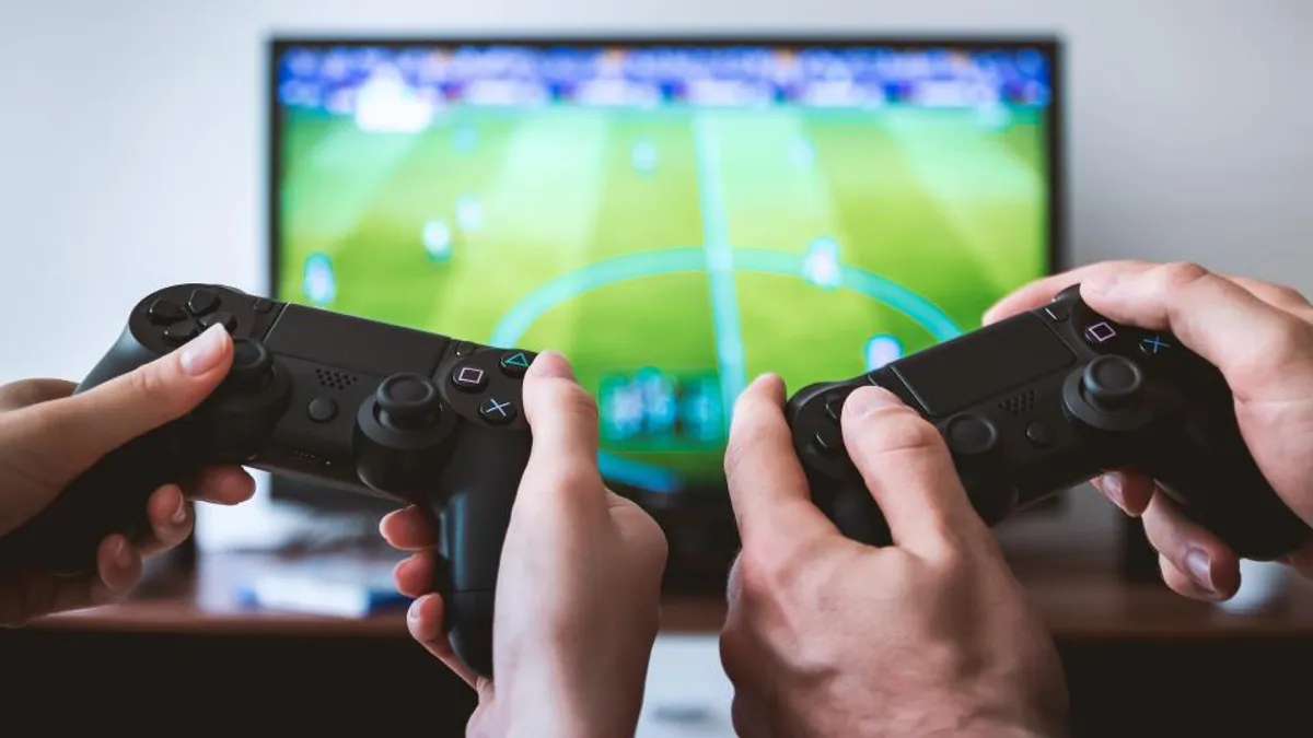 Duas pessoas jogando videogame com controles em frente à TV