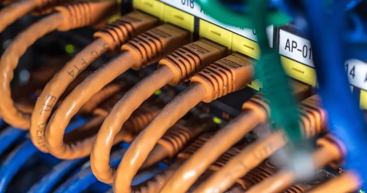 Painel de rede com cabos laranja conectados a um switch