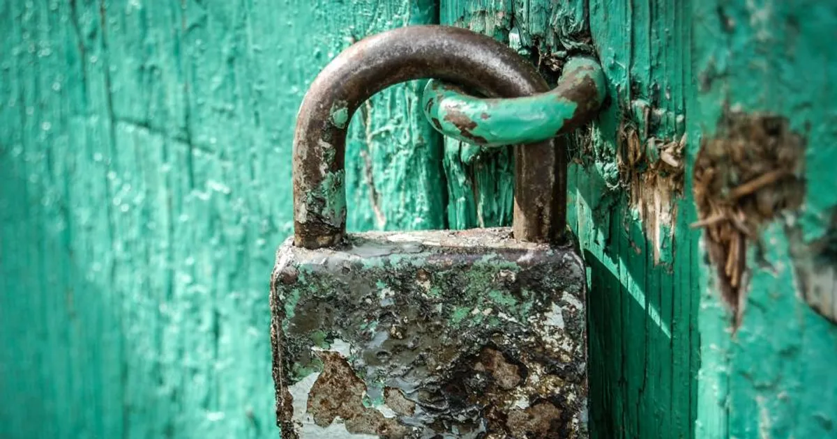 Cadeado antigo trancando uma porta de madeira verde